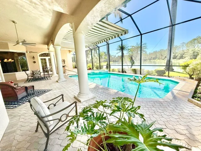 View of swimming pool featuring a patio area, glass enclosure, ceiling fan, and a water view