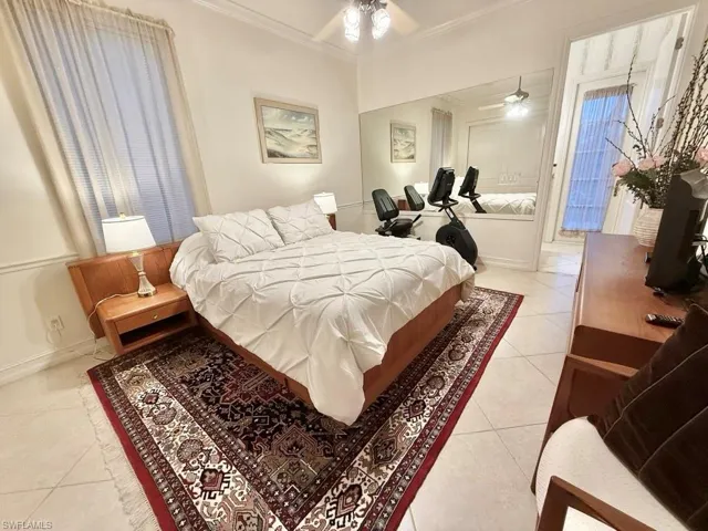 Tiled bedroom with ornamental molding and ceiling fan