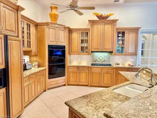 Kitchen featuring tasteful backsplash, stainless steel gas stovetop, sink, black double oven, and crown molding