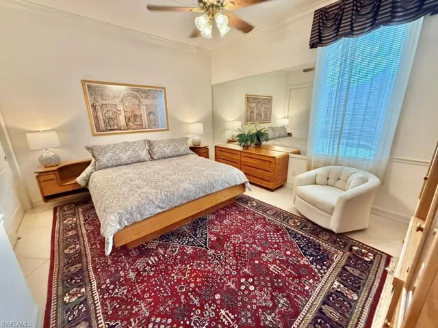 Bedroom featuring multiple windows, light tile patterned floors, ornamental molding, and ceiling fan