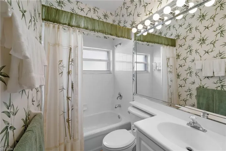 Full bathroom with toilet, shower / bath combination with curtain, and vanity