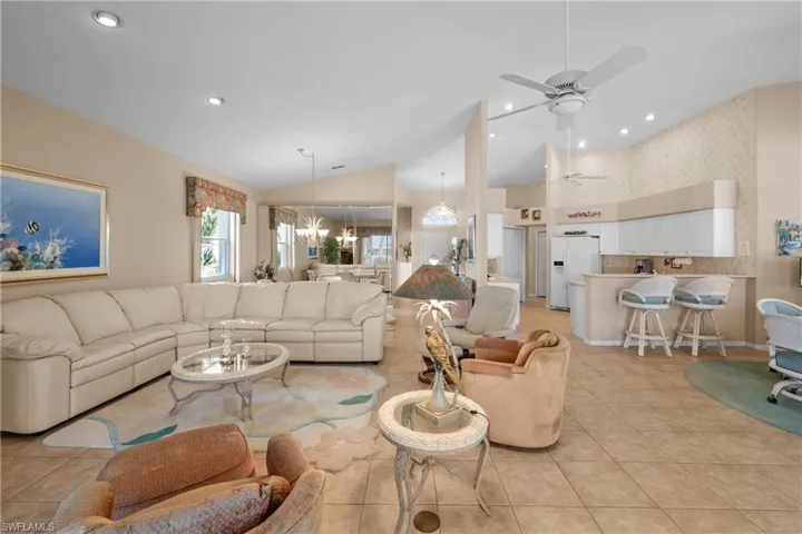 Living room with light tile flooring, vaulted ceiling, and ceiling fan.