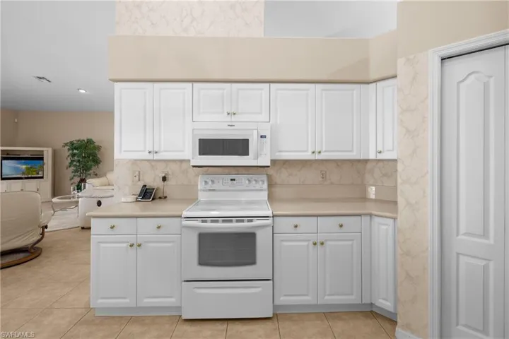 Kitchen with range with electric cooktop, white cabinets, and light tile floors