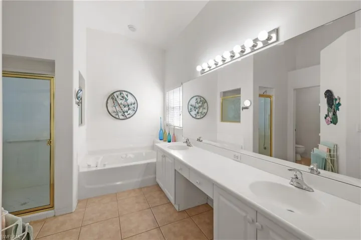 Full primary bathroom with plus walk in shower, toilet, vanity, high vaulted ceiling, and tile flooring