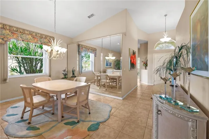 Dining space featuring high vaulted ceiling, a notable chandelier, and light tile floors