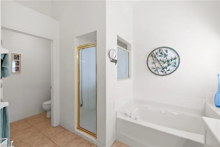 Bathroom with tile flooring, toilet room, and separate shower and soaking tub