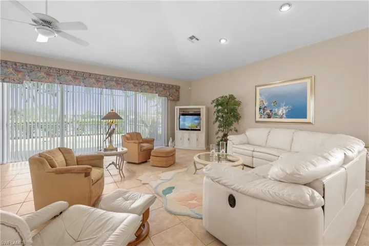 Tiled living room with ceiling fan and full wall sliding glass doors.
