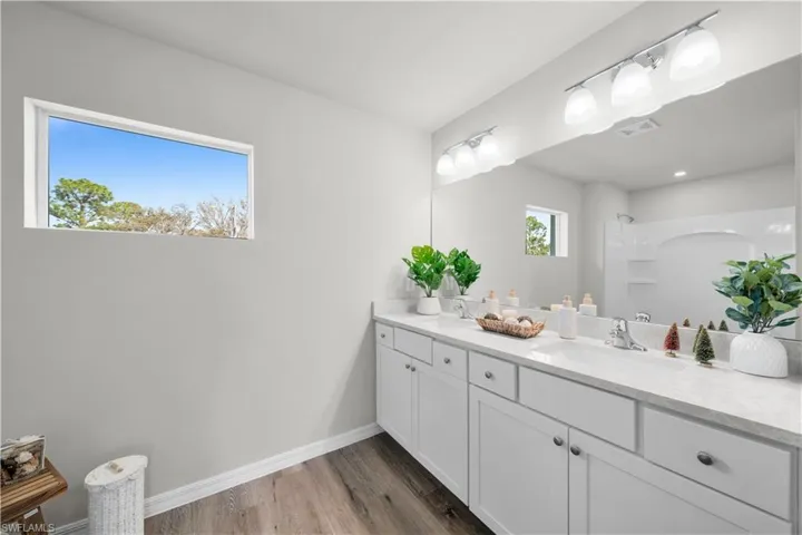 Full bath featuring wood finished floors, a sink, visible vents, and baseboards