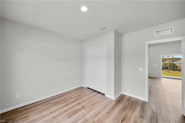 Unfurnished bedroom featuring baseboards, visible vents, and wood finished floors
