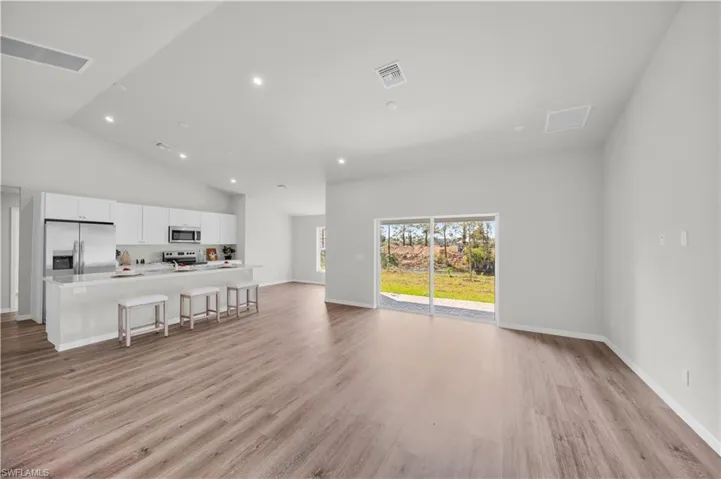 Living room with light wood-type flooring, visible vents, baseboards, and recessed lighting