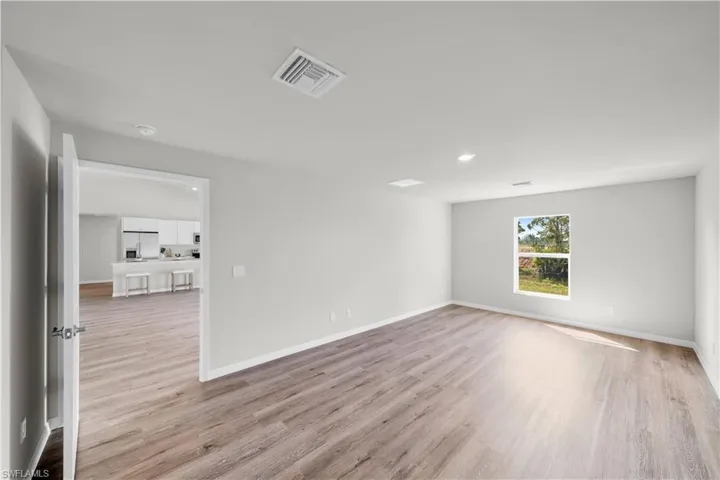 Unfurnished room with light wood finished floors, visible vents, and baseboards