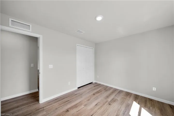 Unfurnished bedroom with baseboards, a closet, visible vents, and wood finished floors