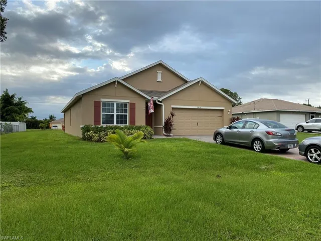 Ranch-style home featuring stucco siding, a front lawn, a garage, and concrete driveway