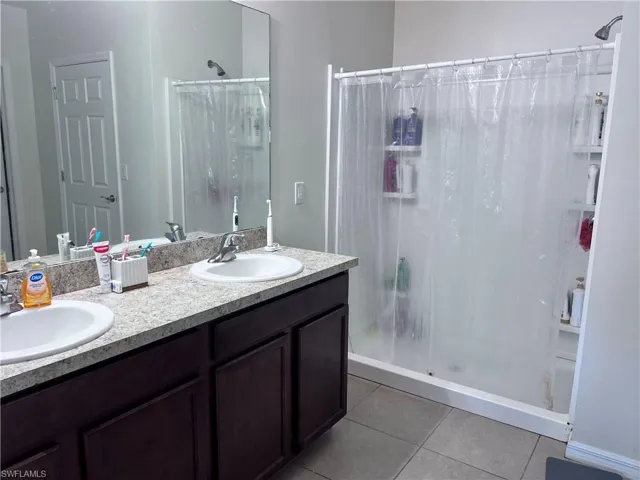 Bathroom with double vanity, a stall shower, and light tile patterned floors