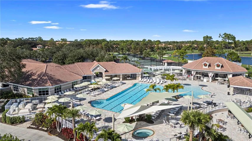 Community pool featuring a patio, view of scattered trees, a water view, and a hot tub