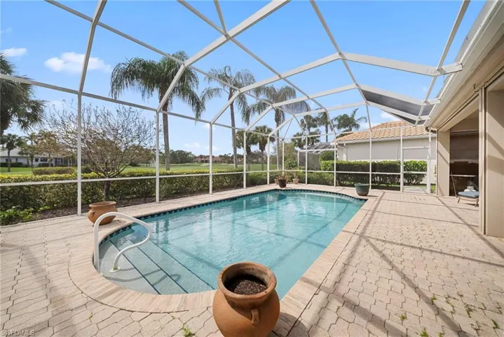 Swimming pool featuring a sunroom, a patio area, and glass enclosure