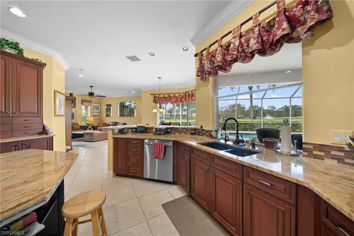 Kitchen featuring crown molding, pendant lighting, stainless steel dishwasher, a sunroom, and ceiling fan