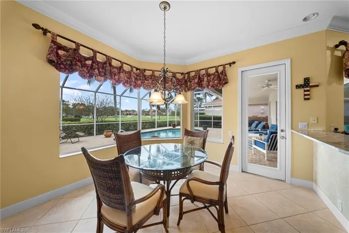 Dining room with light tile patterned flooring, a sunroom, crown molding, and hanging lights