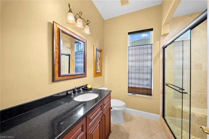 Full bath featuring a shower stall, vanity, and light tile patterned flooring