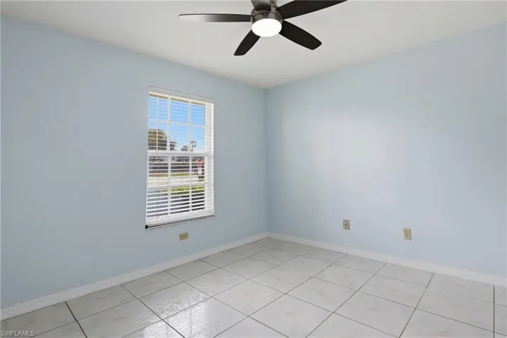 Empty room featuring a ceiling fan and light tile patterned floors