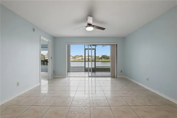 Unfurnished room with ceiling fan, a water view, and light tile patterned floors