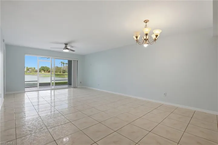 Spare room featuring a chandelier, a ceiling fan, a water view, and light tile patterned flooring