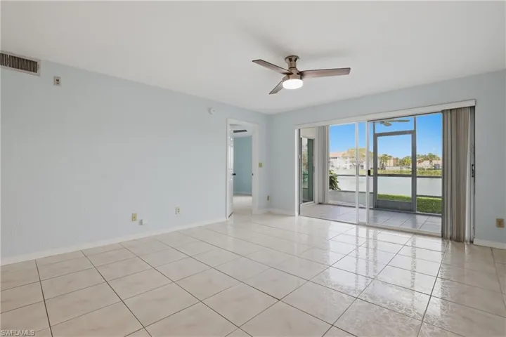 Empty room with a ceiling fan, a water view, and light tile patterned flooring