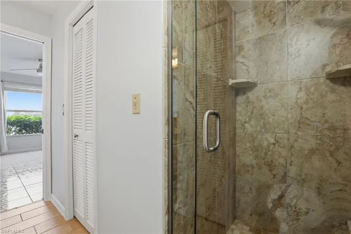 Full bath featuring a closet, a stall shower, and light wood-type flooring