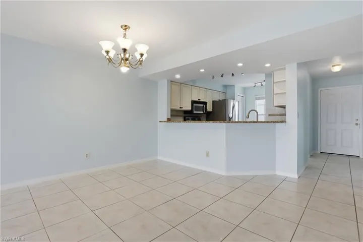 Kitchen featuring a chandelier, a peninsula, dark stone countertops, open shelves, and light tile patterned floors