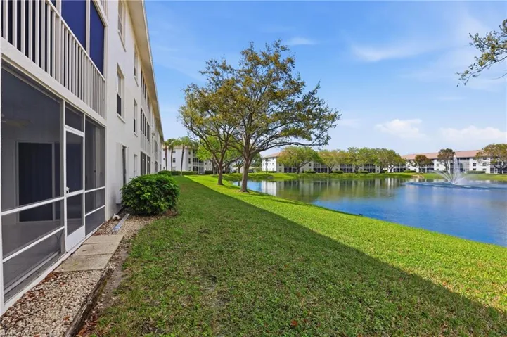 View of grassy yard featuring a sunroom and a water view