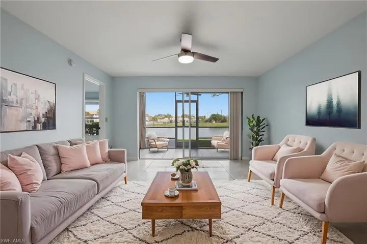 Tiled living room featuring ceiling fan and a water view