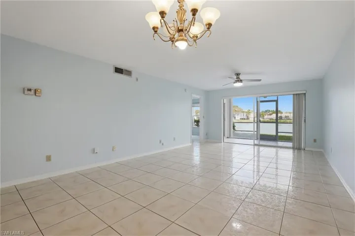 Unfurnished room with a chandelier, a water view, a ceiling fan, and light tile patterned flooring
