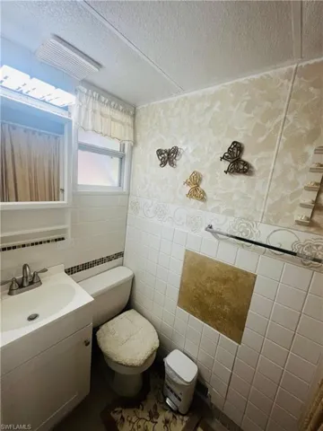 Bathroom featuring tile walls, vanity, and a textured ceiling