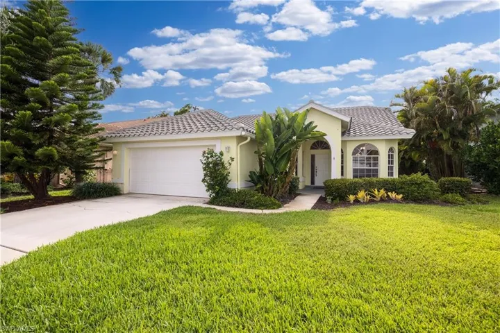 Single-story residence featuring a tile roof, light-toned exterior, arched windows, and an attached two-car garage