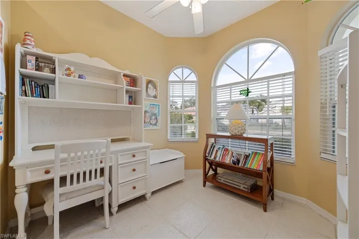 Arched windows with louvered blinds frame the space, complemented by a ceiling fan with integrated lighting