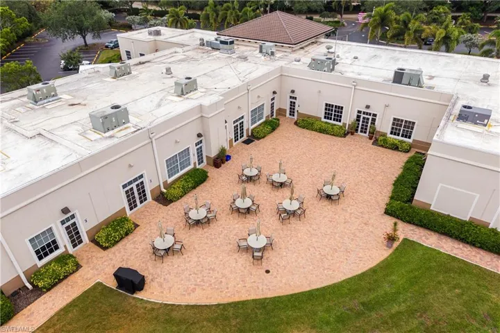 Expansive outdoor courtyard featuring a textured paver surface and surrounding manicured landscaping