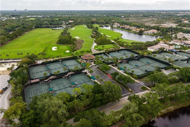 Expansive tennis court complex featuring multiple hard courts, a central clubhouse structure, and surrounding tropical landscaping