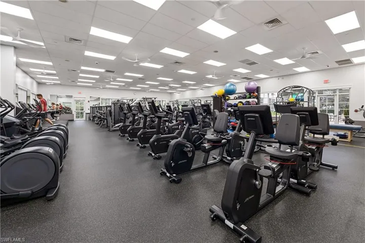 Spacious fitness center featuring robust exercise equipment, high ceilings with recessed lighting, and multiple ceiling fans