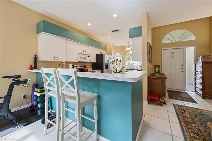 Kitchen with white cabinetry, microwave, and refrigerator