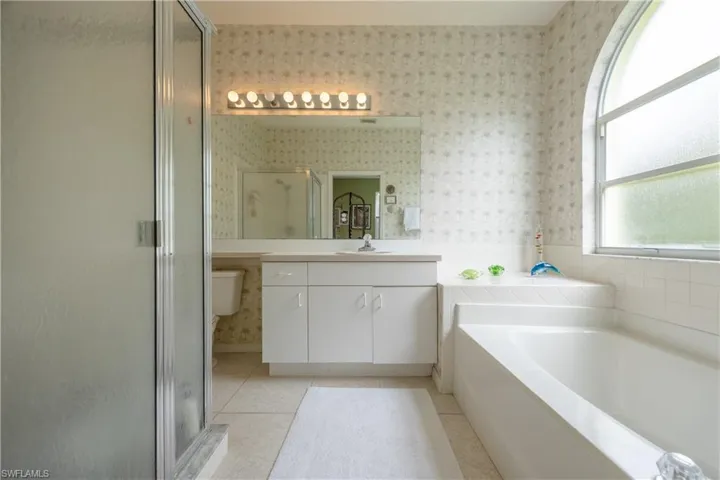 Bathroom featuring a white vanity with integrated sink, a large mirror, and a multi-bulb light fixture