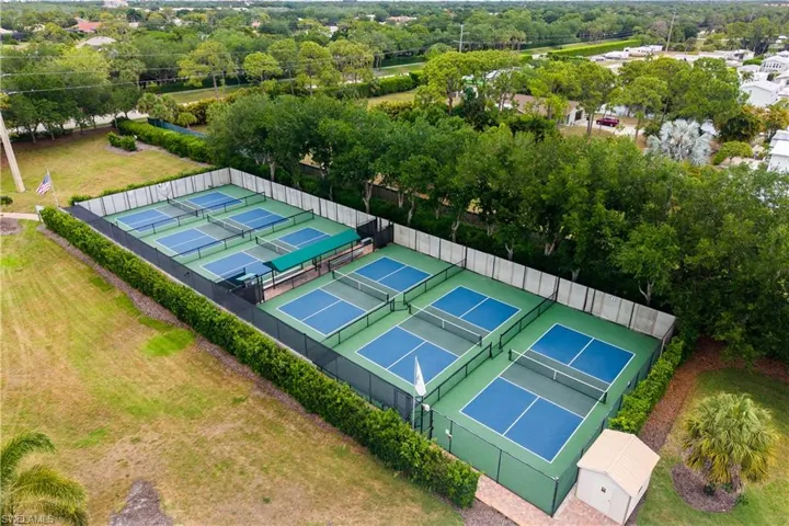 Eight pickleball courts with blue playing surfaces and green surrounds