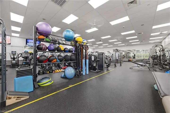 Spacious fitness center featuring rubberized flooring, comprehensive weight training equipment, mirrored walls, and recessed ceiling lighting