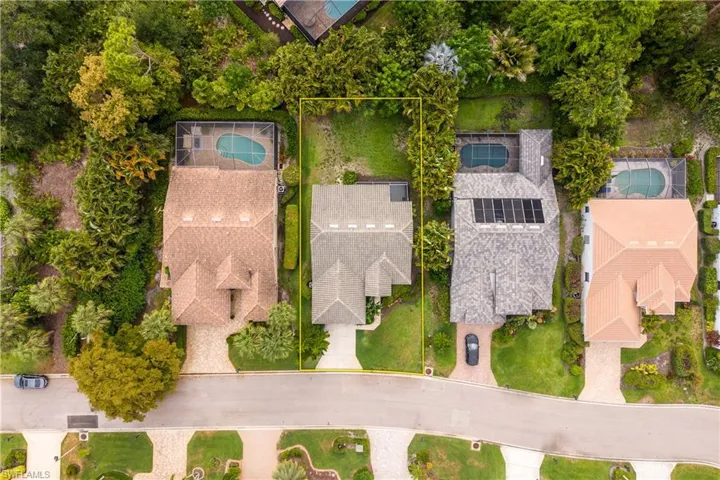 Aerial perspective of a residential property featuring a gray shingle roof, a two-car driveway, and a partially visible front yard