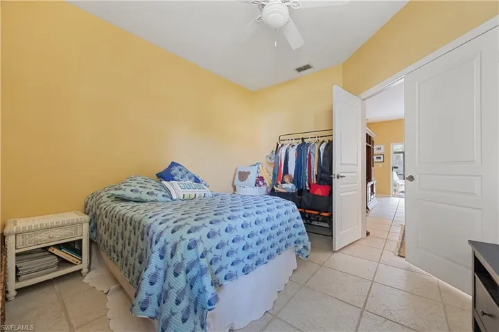 Room featuring vaulted ceilings, light-toned tile flooring, and a ceiling fan