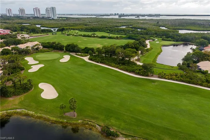 Expansive golf course featuring multiple sand traps, a putting green, and a water feature