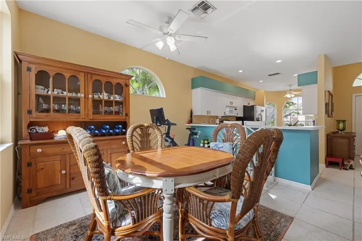 Dining area featuring a wooden hutch with glass-front display cabinets, tile flooring, and a ceiling fan