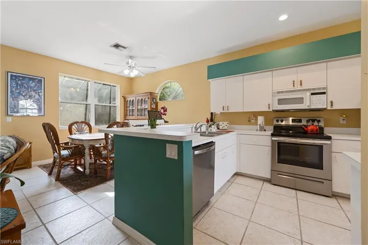 Kitchen featuring white cabinetry, light-toned countertops, and stainless steel appliances including a range, microwave, and dishwasher