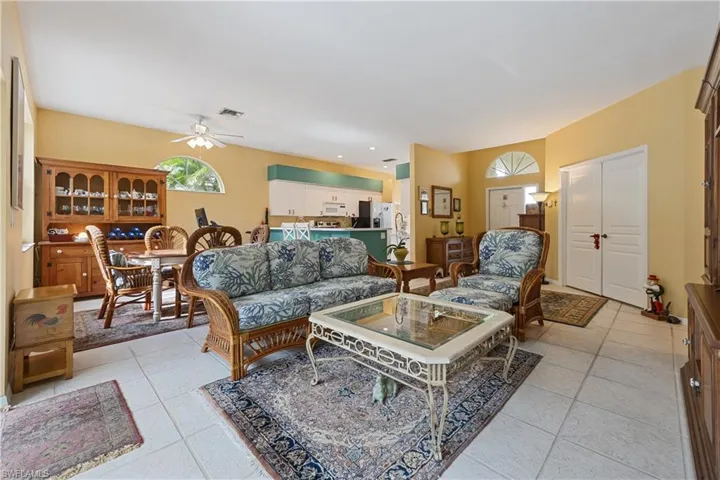 Open-concept living space featuring light-toned tile flooring, a dining area with a built-in hutch, and a kitchen with white cabinetry and a breakfast bar