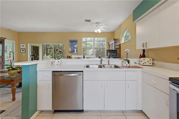 Kitchen featuring white cabinetry and countertops, a stainless steel dishwasher, and a dual basin sink