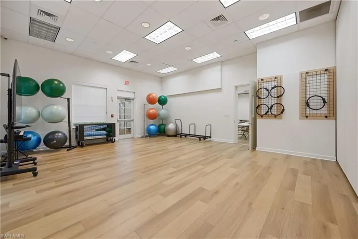 Spacious fitness studio featuring wood-finish flooring, recessed lighting, and a white drop ceiling